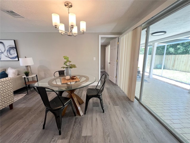 3304 Honeymoon Ln, Holiday, FL 34691 - dining room with a chandelier, light wood-style flooring, and a textured ceiling