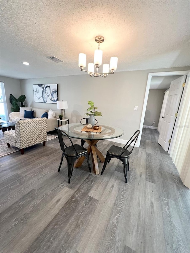 3304 Honeymoon Ln, Holiday, FL 34691 - dining area with a chandelier, wood finished floors, a textured ceiling, and baseboards