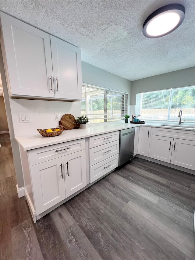 3304 Honeymoon Ln, Holiday, FL 34691 - kitchen with stainless steel dishwasher, a sink, light countertops, a textured ceiling, and white cabinetry