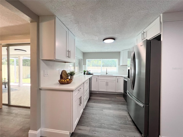 3304 Honeymoon Ln, Holiday, FL 34691 - kitchen featuring stainless steel appliances, light countertops, white cabinets, a sink, and a textured ceiling