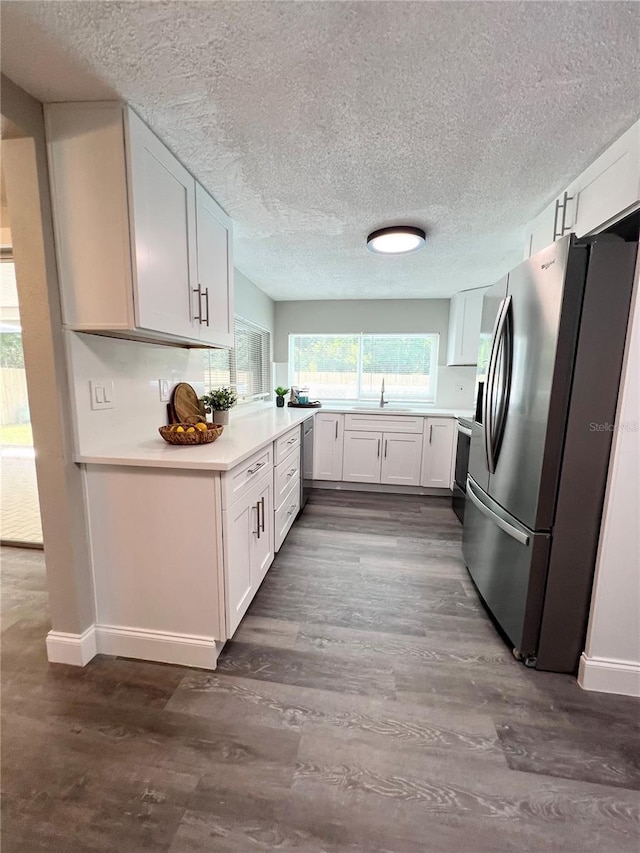 3304 Honeymoon Ln, Holiday, FL 34691 - kitchen with stainless steel appliances, a sink, dark wood-style floors, a textured ceiling, and baseboards
