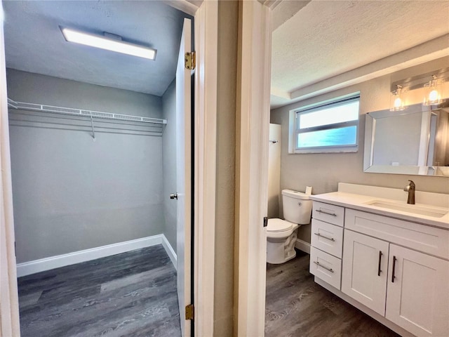 3304 Honeymoon Ln, Holiday, FL 34691 - full bath featuring wood finished floors, a walk in closet, vanity, toilet, and baseboards
