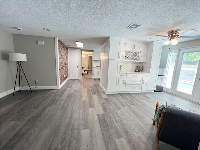 3304 Honeymoon Ln, Holiday, FL 34691 - unfurnished living room with baseboards, a textured ceiling, light wood-type flooring, ceiling fan, and a dry bar