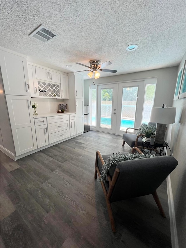 3304 Honeymoon Ln, Holiday, FL 34691 - living room with a textured ceiling, french doors, dark wood-style flooring, ceiling fan, and a bar