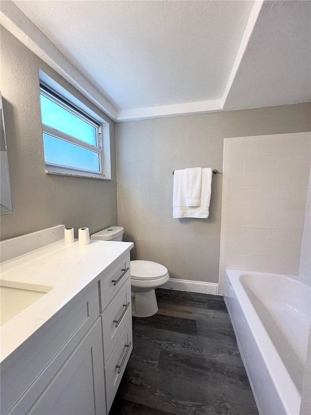 3304 Honeymoon Ln, Holiday, FL 34691 - bathroom with vanity, a tub to relax in, toilet, wood finished floors, and baseboards