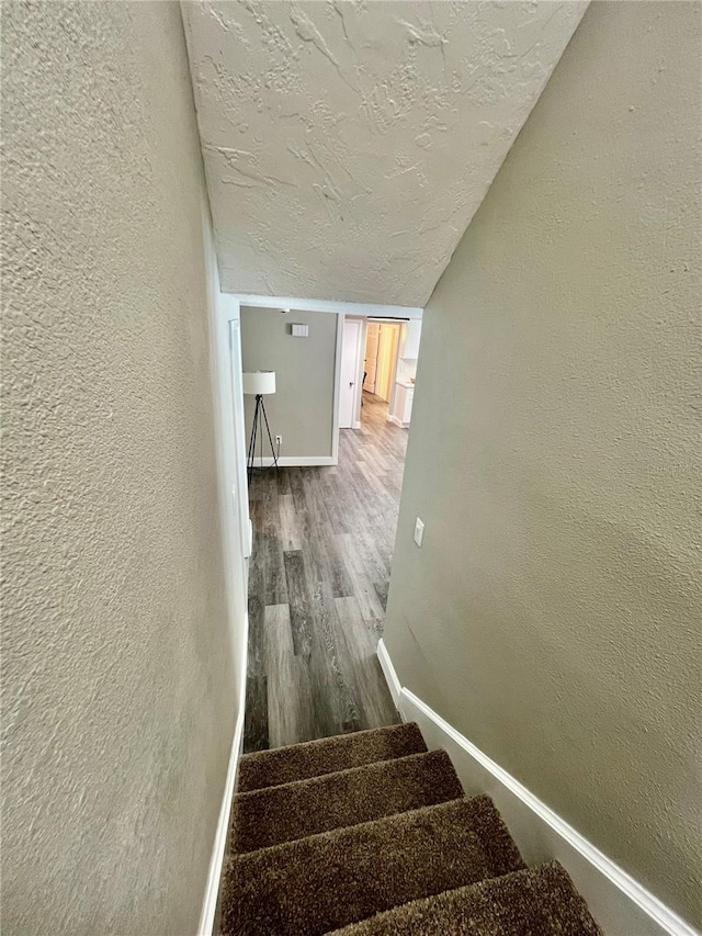3304 Honeymoon Ln, Holiday, FL 34691 - staircase with a textured wall, wood finished floors, a textured ceiling, baseboards, and vaulted ceiling