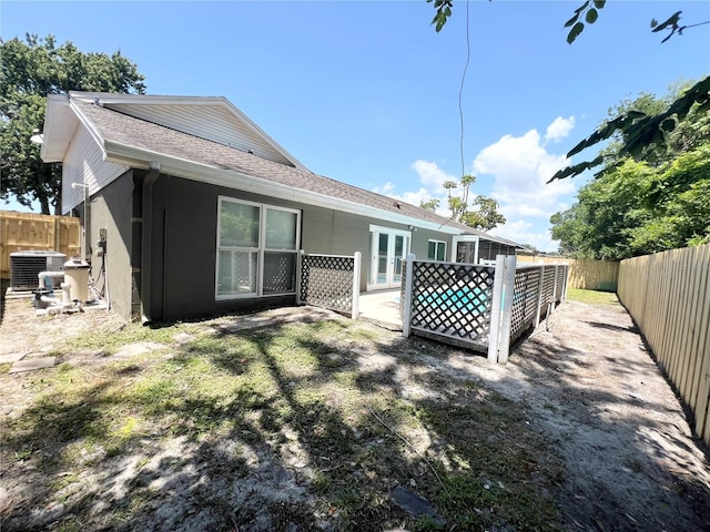 3304 Honeymoon Ln, Holiday, FL 34691 - back of property featuring a fenced backyard, roof with shingles, and central AC