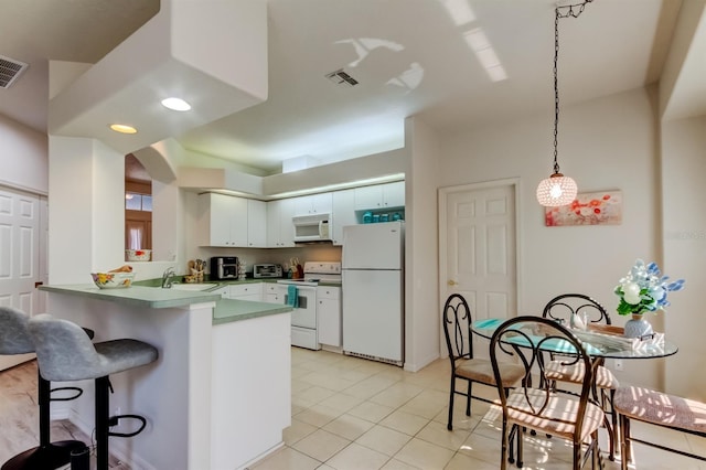 14466 Tamarind Loop, Spring Hill, FL 34609 - kitchen featuring white appliances, a peninsula, a breakfast bar area, light tile patterned floors, and a sink