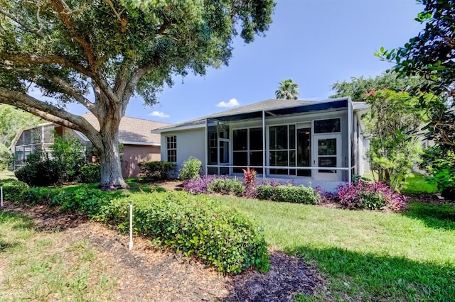 14466 Tamarind Loop, Spring Hill, FL 34609 - back of house with a yard, stucco siding, a sunroom, and roof with shingles