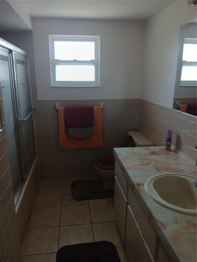 9516 Glen Moor Ln, Port Richey, FL 34668 - bathroom featuring tile walls, vanity, toilet, tile patterned flooring, and enclosed tub / shower combo