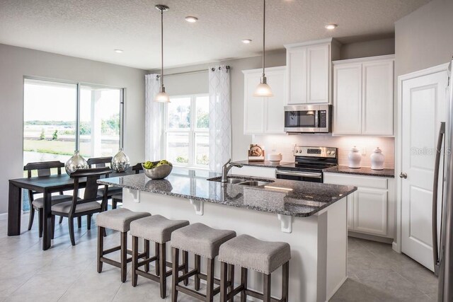 1681 W Palms Dr, Port Charlotte, FL 33953 - kitchen featuring appliances with stainless steel finishes, a sink, dark stone countertops, a kitchen bar, and a textured ceiling
