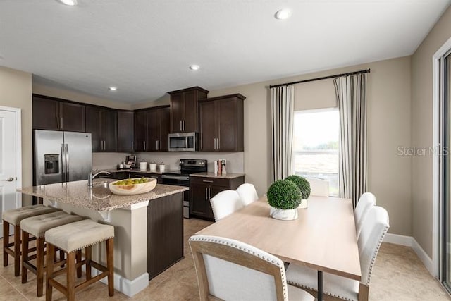 1723 W Palms Dr, Port Charlotte, FL 33953 - kitchen with appliances with stainless steel finishes, dark brown cabinets, an island with sink, a kitchen breakfast bar, and recessed lighting