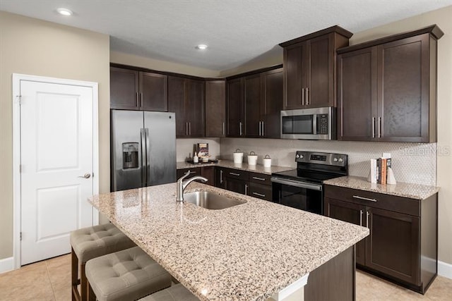 1723 W Palms Dr, Port Charlotte, FL 33953 - kitchen featuring stainless steel appliances, a sink, light stone counters, dark brown cabinetry, and a breakfast bar