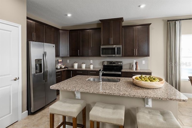 1723 W Palms Dr, Port Charlotte, FL 33953 - kitchen with appliances with stainless steel finishes, a sink, dark brown cabinets, light stone counters, and light tile patterned floors