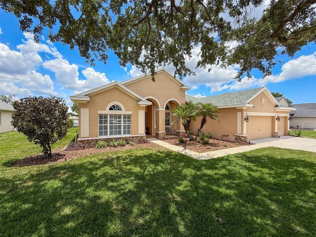 13248 Linzia Ln, Spring Hill, FL 34609 - view of front of house with stucco siding, concrete driveway, a garage, a front lawn, and stone siding