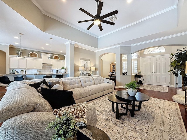 13248 Linzia Ln, Spring Hill, FL 34609 - living room featuring arched walkways, ceiling fan, dark wood finished floors, crown molding, and decorative columns