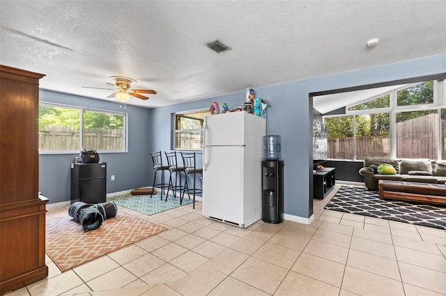 8634 Roble Way, Port Richey, FL 34668 - kitchen with freestanding refrigerator, a ceiling fan, healthy amount of natural light, light tile patterned floors, and a textured ceiling