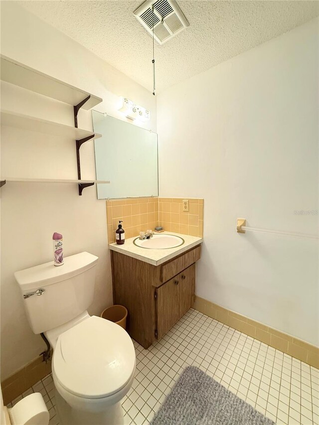 11034 Harding Dr, Port Richey, FL 34668 - half bathroom with vanity, toilet, tile patterned floors, a textured ceiling, and decorative backsplash