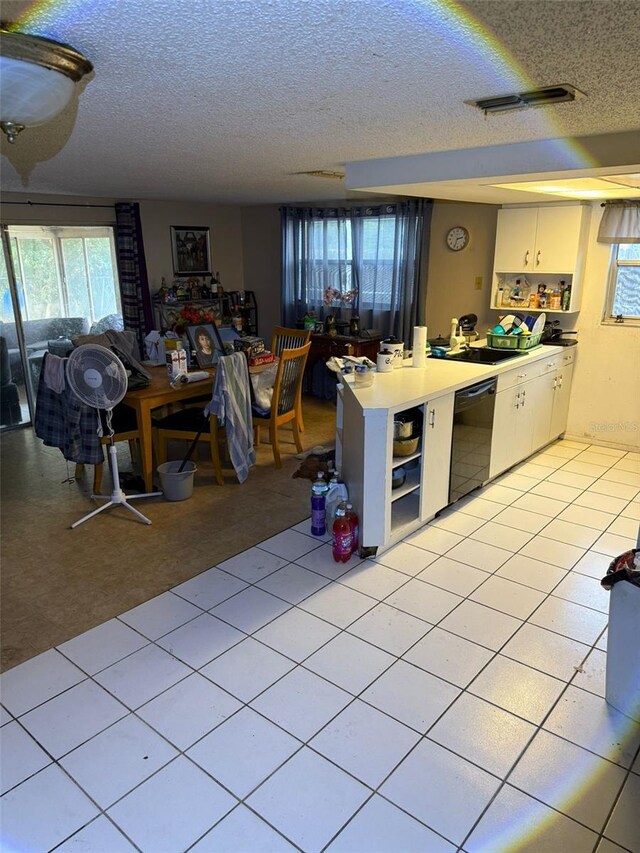 11726 Oceanside Dr, Port Richey, FL 34668 - kitchen featuring black dishwasher, healthy amount of natural light, a textured ceiling, a peninsula, and white cabinetry