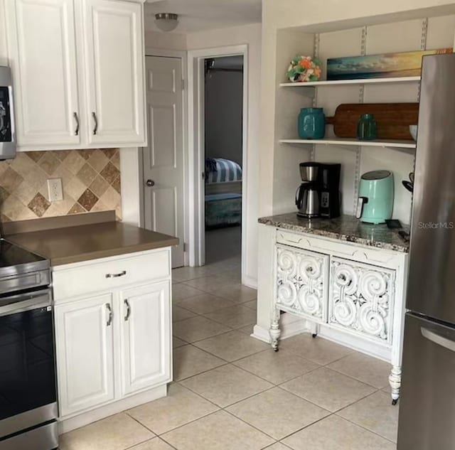 6603 Adams St, New Port Richey, FL 34652 - kitchen featuring stainless steel appliances, light tile patterned floors, decorative backsplash, and dark countertops