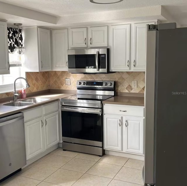 6603 Adams St, New Port Richey, FL 34652 - kitchen with appliances with stainless steel finishes, a sink, backsplash, light tile patterned floors, and a textured ceiling