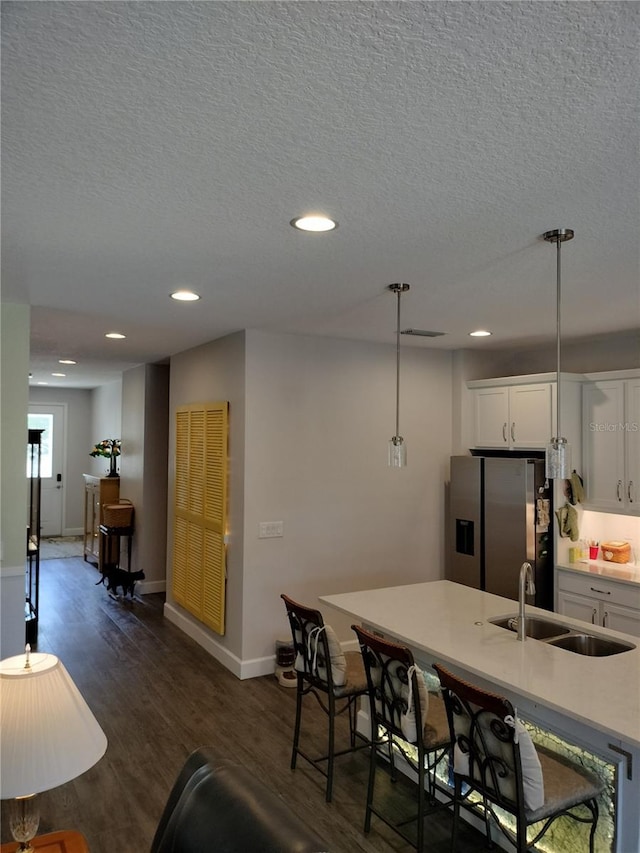 9967 Patrician Dr, New Port Richey, FL 34655 - kitchen featuring a sink, stainless steel refrigerator with ice dispenser, dark wood-style flooring, a textured ceiling, and white cabinets