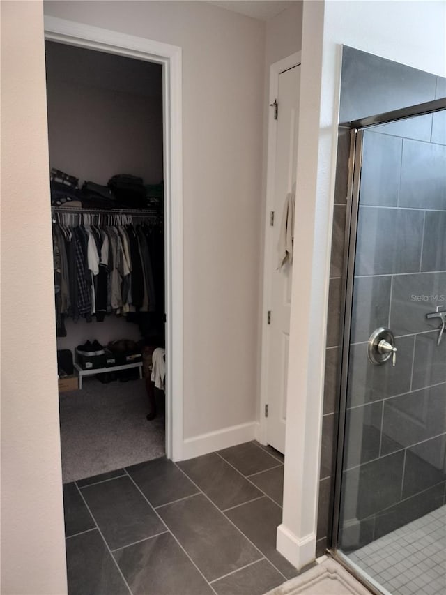 9967 Patrician Dr, New Port Richey, FL 34655 - bathroom featuring a shower stall, a walk in closet, tile patterned floors, and baseboards