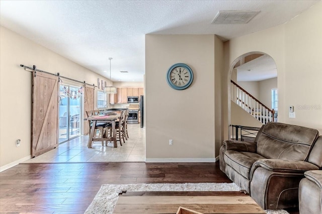 4094 Braemere Dr, Spring Hill, FL 34609 - living area with light wood-type flooring, arched walkways, baseboards, and a barn door