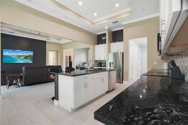 10380 Yellow Hammer Rd, Weeki Wachee, FL 34614 - kitchen featuring appliances with stainless steel finishes, a raised ceiling, dark stone counters, ornamental molding, and a kitchen breakfast bar