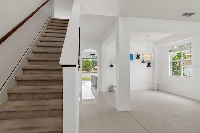 4215 Maplehurst Way, Spring Hill, FL 34609 - stairway featuring tile patterned floors, a chandelier, baseboards, and arched walkways