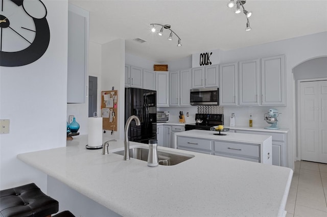 4215 Maplehurst Way, Spring Hill, FL 34609 - kitchen featuring black appliances, a sink, a peninsula, light tile patterned flooring, and a kitchen bar