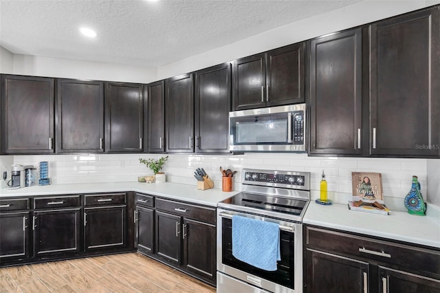 7523 Tangle Brook Blvd, Gibsonton, FL 33534 - kitchen featuring appliances with stainless steel finishes, light countertops, light wood finished floors, a textured ceiling, and backsplash