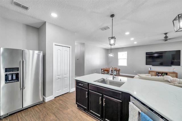 7523 Tangle Brook Blvd, Gibsonton, FL 33534 - kitchen featuring appliances with stainless steel finishes, a sink, wood finished floors, a textured ceiling, and baseboards