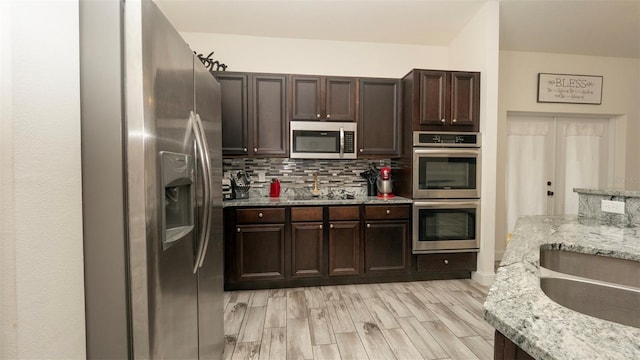 12458 Fish Cove Dr, Spring Hill, FL 34609 - kitchen with stainless steel appliances, tasteful backsplash, dark brown cabinets, and light stone countertops