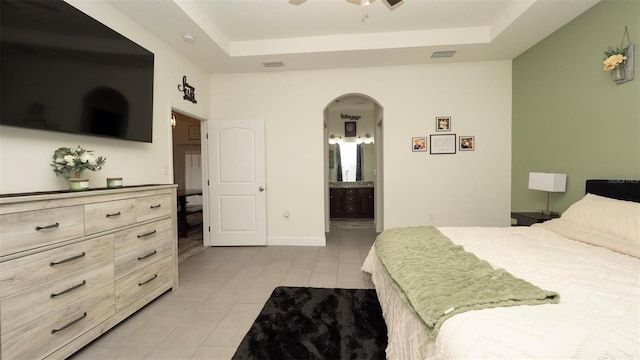 12458 Fish Cove Dr, Spring Hill, FL 34609 - bedroom featuring light tile patterned floors, a raised ceiling, arched walkways, and ensuite bath