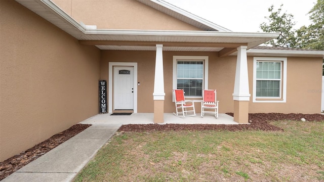 12458 Fish Cove Dr, Spring Hill, FL 34609 - property entrance with covered porch, stucco siding, and a lawn