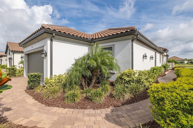 3051 Francoa Dr, Odessa, FL 33556 - view of side of property with an attached garage, stucco siding, and a tiled roof