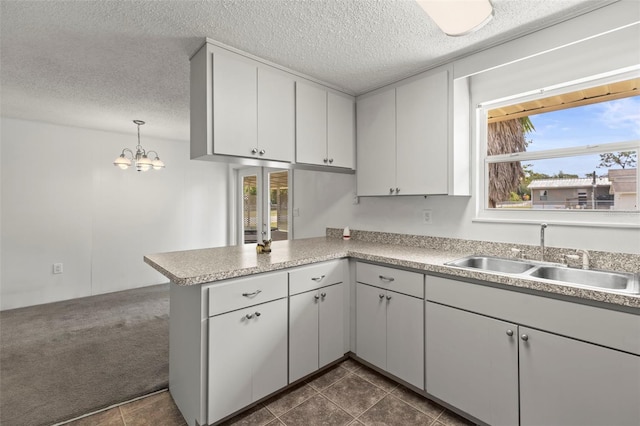 12936 Parkwood St, Hudson, FL 34669 - kitchen with a sink, a peninsula, a textured ceiling, light countertops, and a chandelier