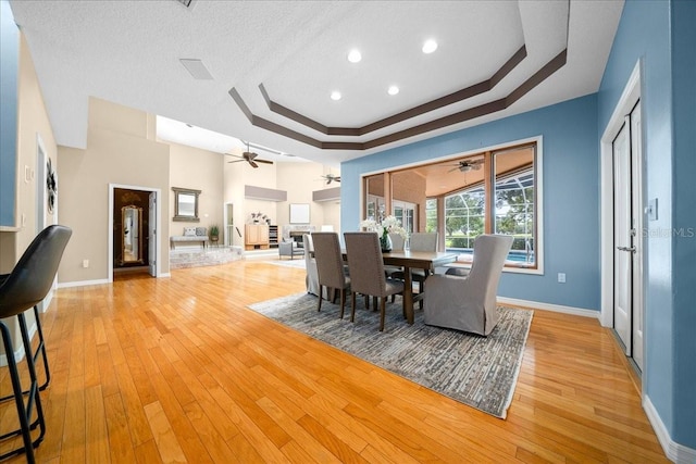 10044 Twelve Oaks Ct, Weeki Wachee, FL 34613 - dining area featuring a tray ceiling, a ceiling fan, light wood-style flooring, baseboards, and a textured ceiling