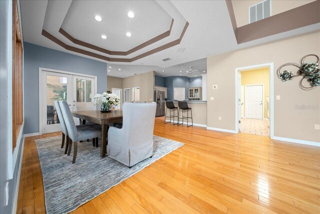 10044 Twelve Oaks Ct, Weeki Wachee, FL 34613 - dining area with a tray ceiling, light wood-type flooring, french doors, baseboards, and recessed lighting