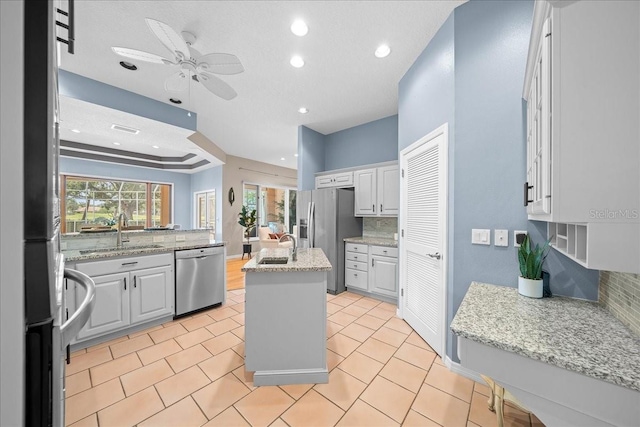 10044 Twelve Oaks Ct, Weeki Wachee, FL 34613 - kitchen with appliances with stainless steel finishes, a sink, a center island with sink, backsplash, and ceiling fan