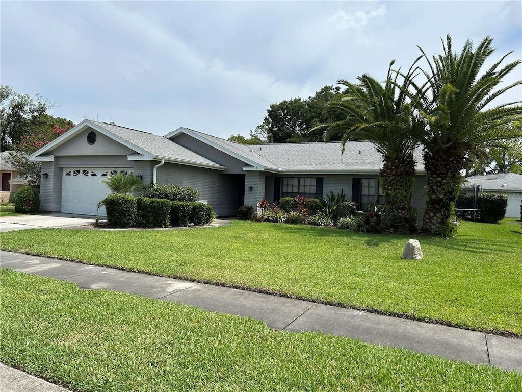 13316 Brigham Ln, Hudson, FL 34667 - ranch-style house featuring an attached garage, a front yard, driveway, brick siding, and a shingled roof