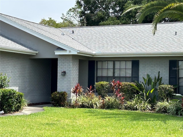 13316 Brigham Ln, Hudson, FL 34667 - doorway to property with roof with shingles, brick siding, and a yard