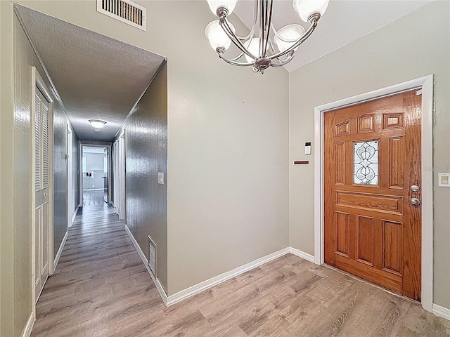 7119 Lenape Cir, New Port Richey, FL 34653 - foyer featuring light wood-style flooring, a chandelier, and baseboards