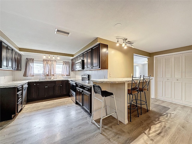 7119 Lenape Cir, New Port Richey, FL 34653 - kitchen with appliances with stainless steel finishes, light wood finished floors, a sink, and a peninsula