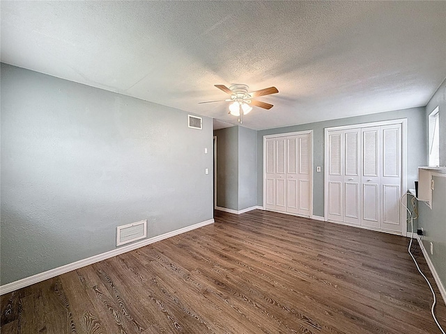 7119 Lenape Cir, New Port Richey, FL 34653 - unfurnished bedroom featuring dark wood-style flooring, two closets, baseboards, a textured ceiling, and ceiling fan