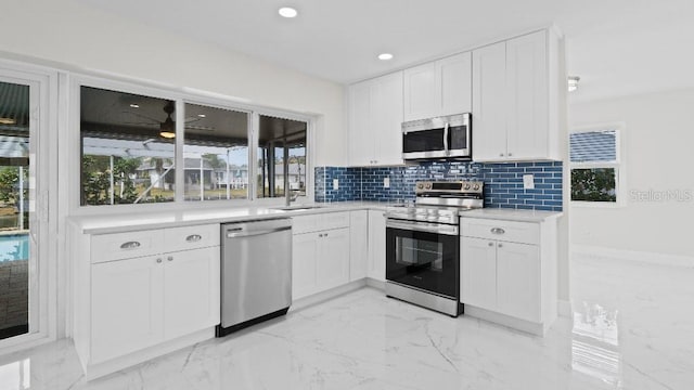 1024 Spindle Palm Way, Apollo Beach, FL 33572 - kitchen featuring stainless steel appliances, light marble finish flooring, white cabinets, healthy amount of natural light, and recessed lighting