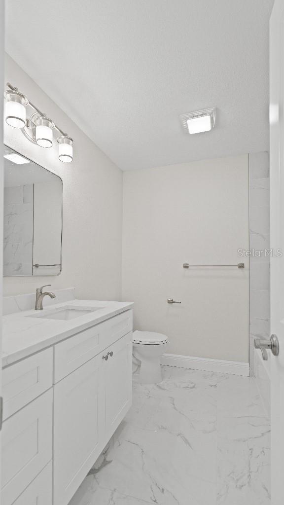 1024 Spindle Palm Way, Apollo Beach, FL 33572 - bathroom featuring vanity, toilet, marble finish flooring, and baseboards