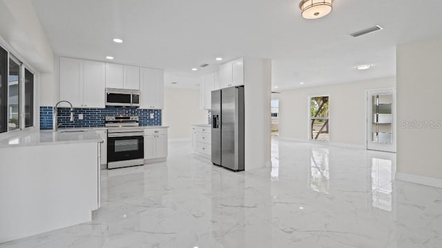 1024 Spindle Palm Way, Apollo Beach, FL 33572 - kitchen with appliances with stainless steel finishes, light marble finish floors, tasteful backsplash, white cabinets, and recessed lighting