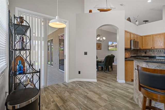 1862 Wood Bend St, Tarpon Springs, FL 34689 - kitchen with dark countertops, decorative backsplash, arched walkways, a towering ceiling, and baseboards